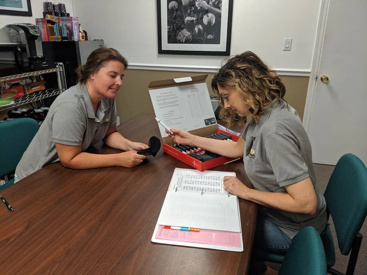 Two indoor air quality professionals reviewing test samples and documentation during an environmental inspection at an office table.