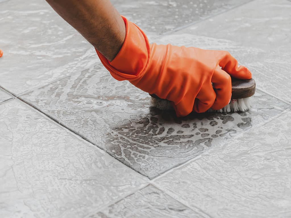 Man cleaning tiles with a brush