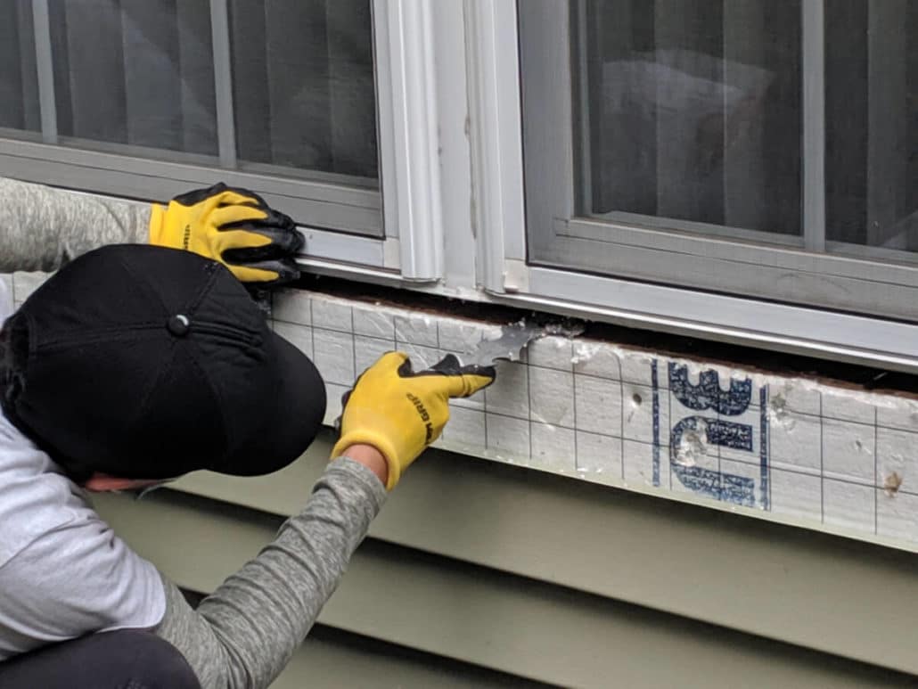 Worker with gloves applying glue to a window