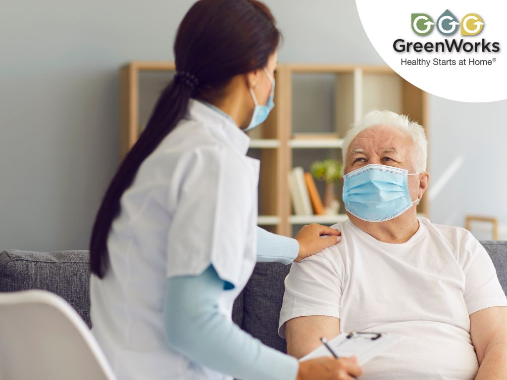 A healthcare professional in a mask provides care and support to an elderly patient in a cozy home setting.