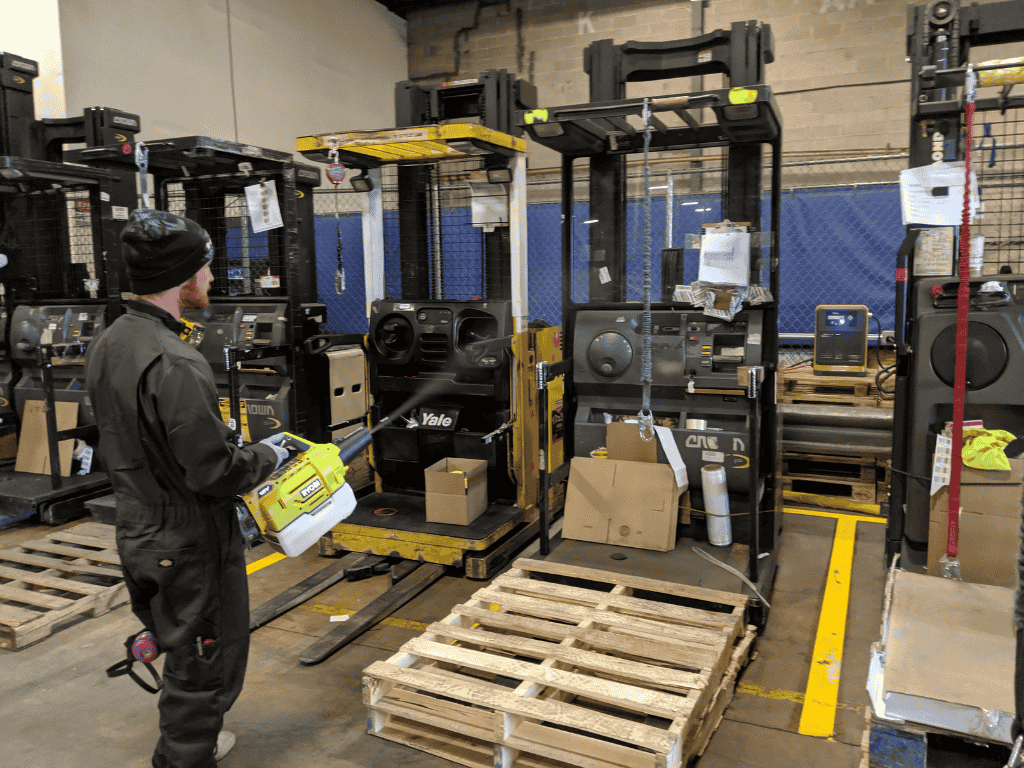 Technician using advanced technology equipment to treat and sanitize industrial workspace.
