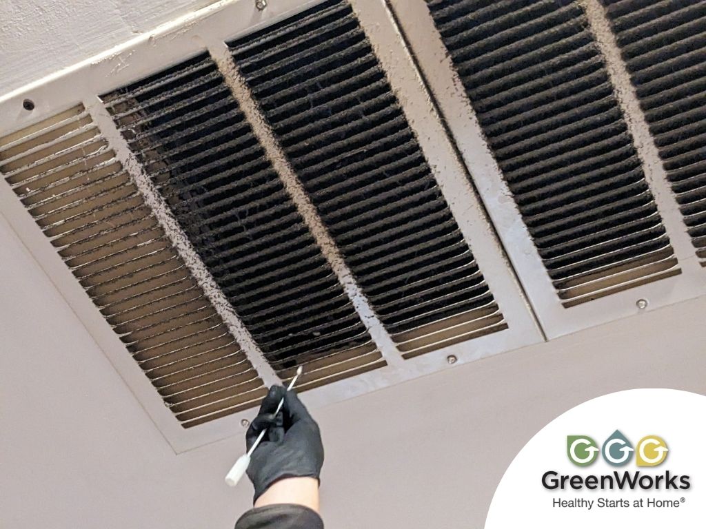 Image showing a technician inspecting an hvac vent with visible dust and mold buildup, emphasizing the importance of mold testing in air ducts for a healthier indoor environment.